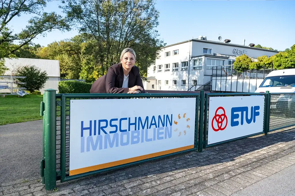 Shary Veldhoen an einem Zaun des ETUF Geländes mit Hirschmann und Etuf Logo